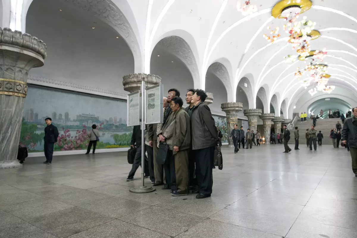 People reading newspapers at Pyongyang subway